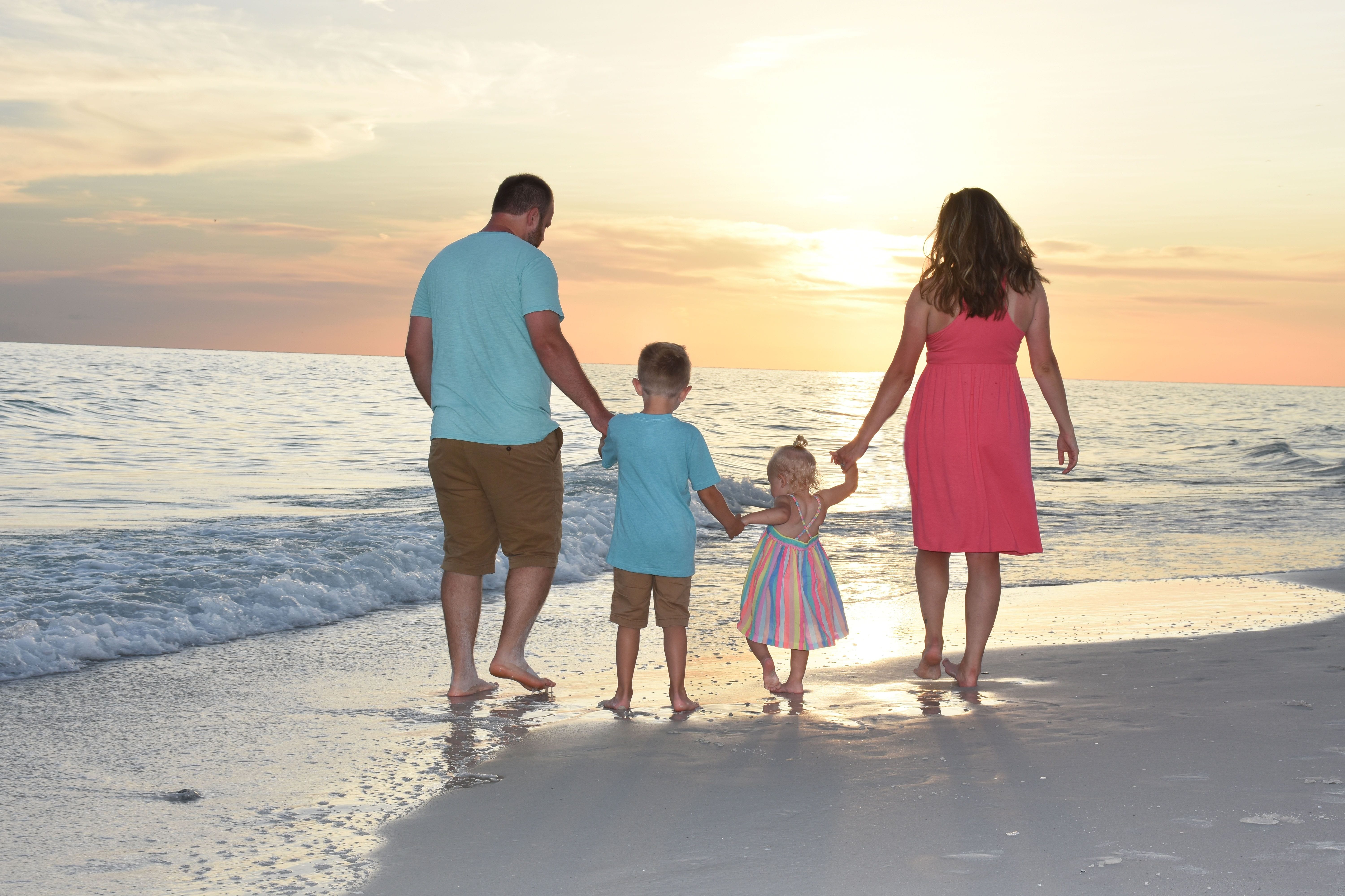 Family walking on beach at sunset